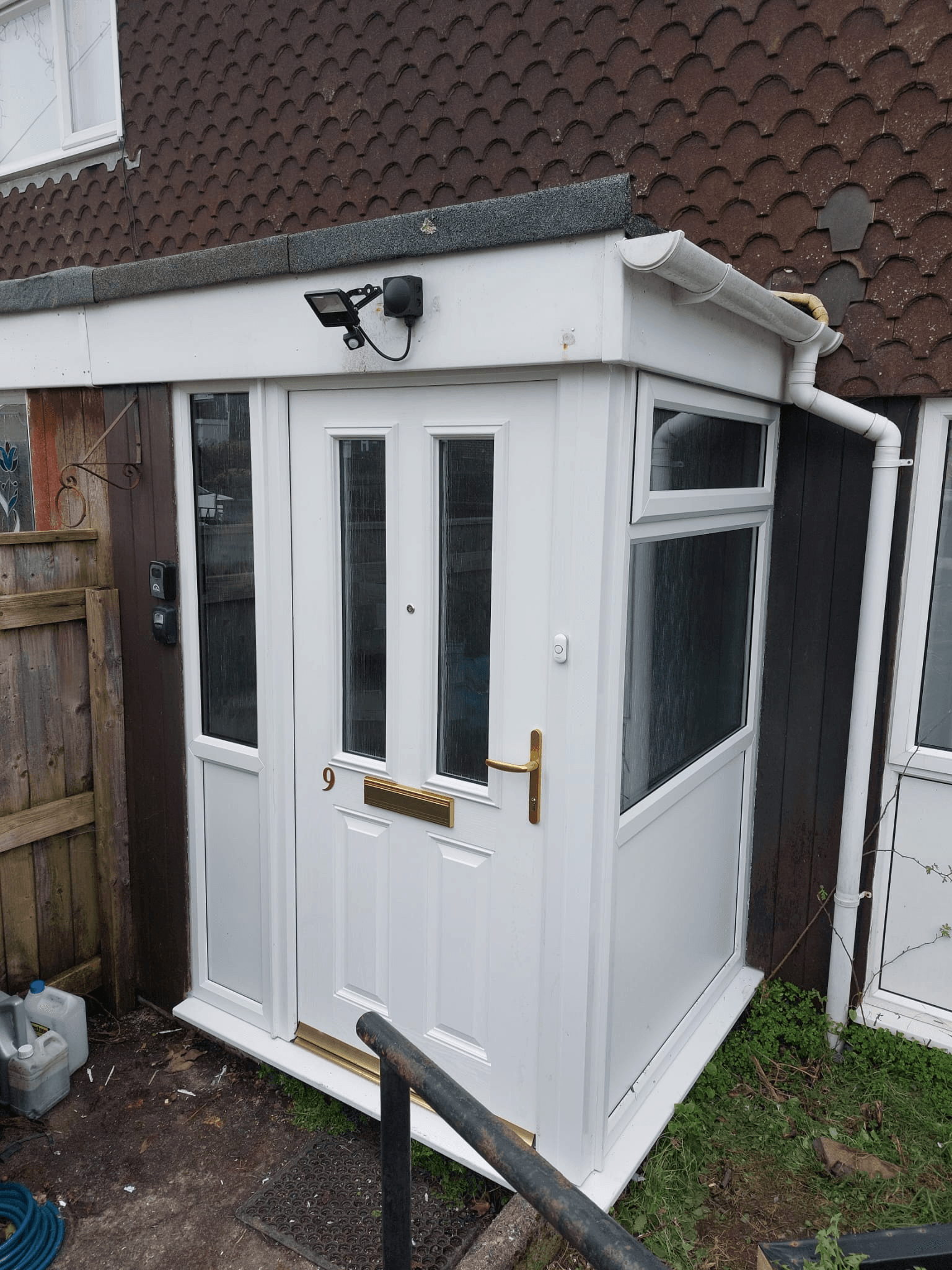 White UPVC door with porch canopy fitted to brick property